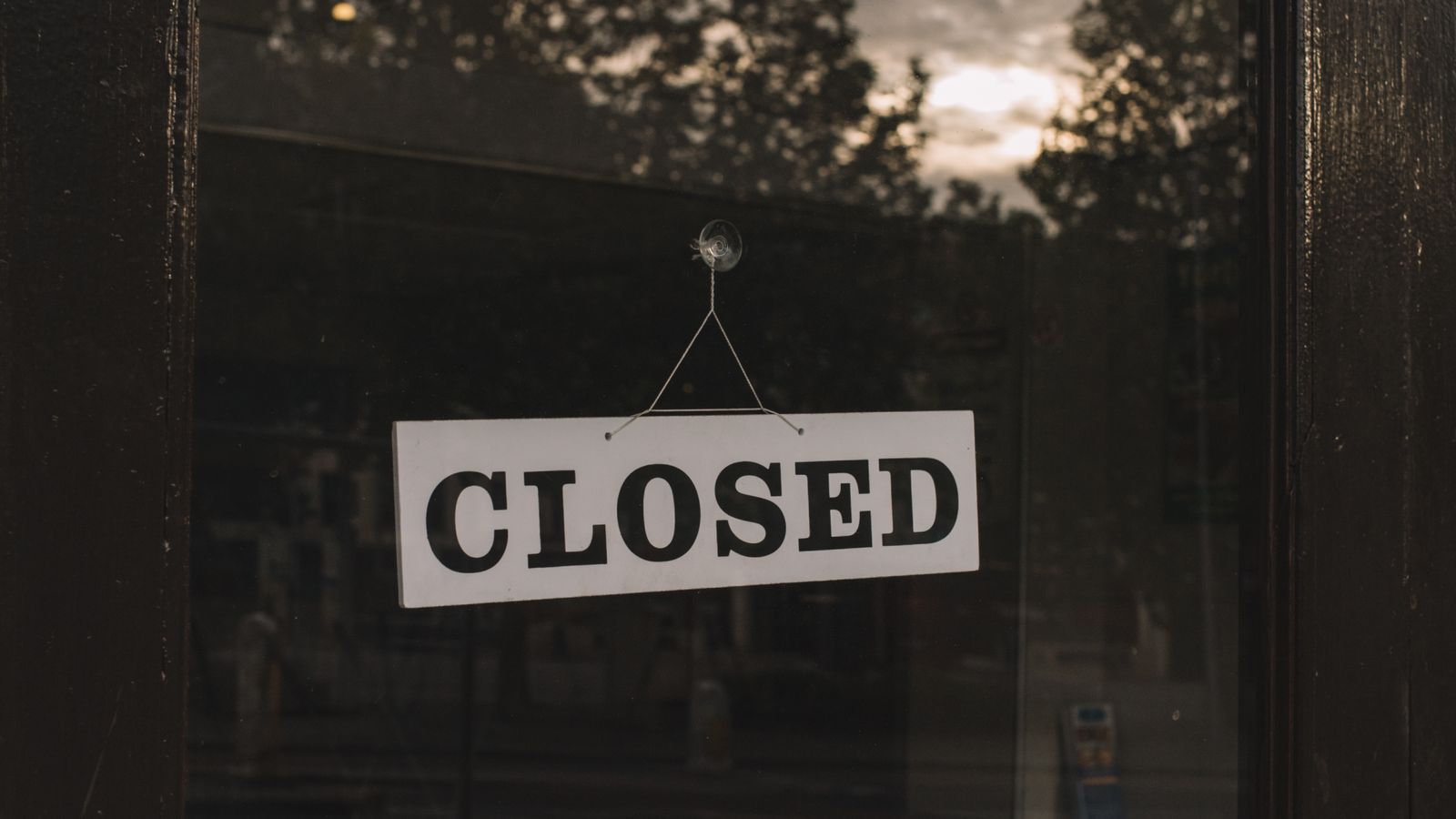 Panneau « Closed » suspendu à la vitrine d'un commerce, symbole d'une fermeture administrative